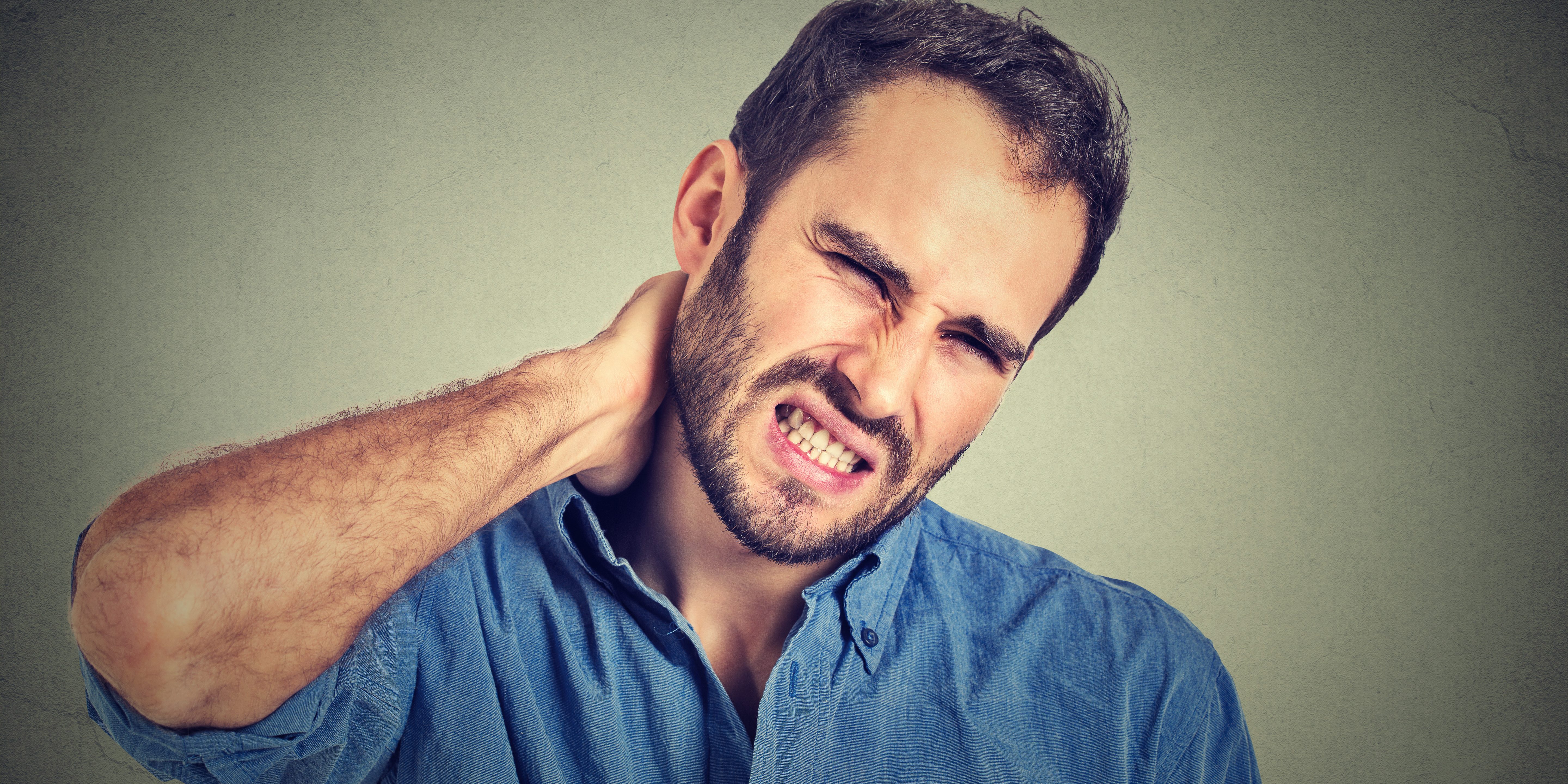 stressed, unhappy young handsome man with bad neck pain